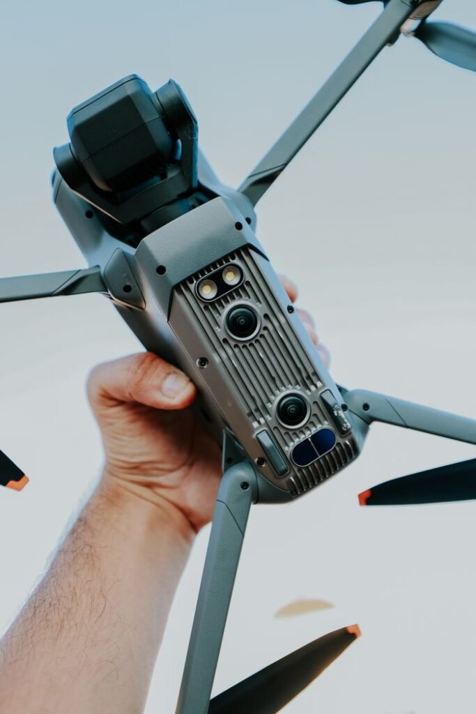 Close-up of a hand holding a sophisticated drone with cameras, outdoors.