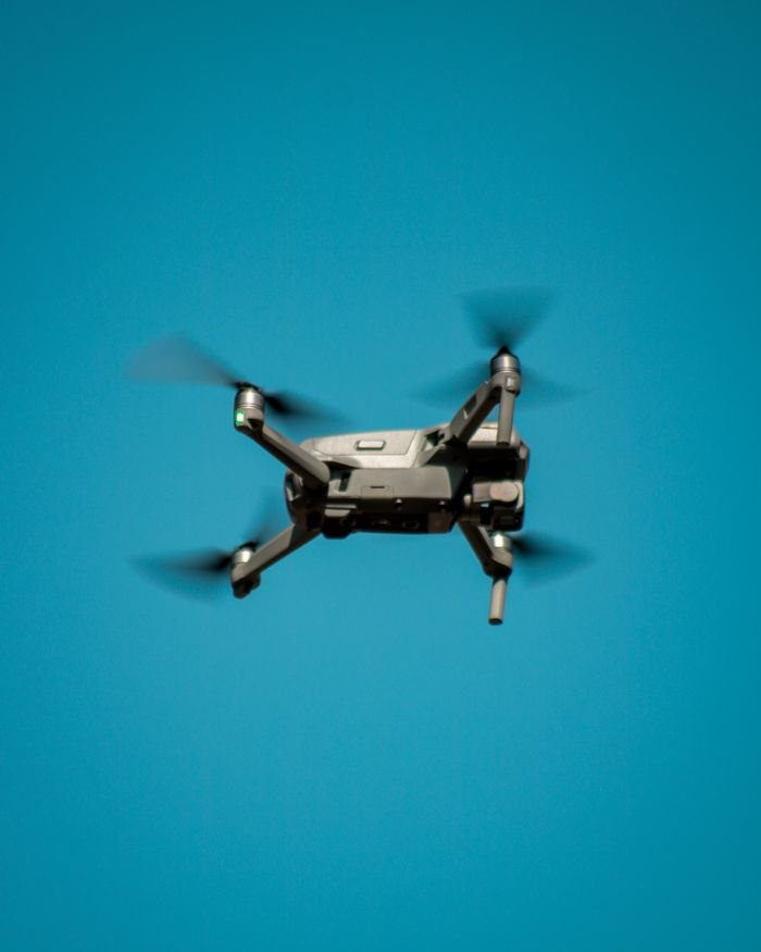 A modern drone flying against a clear blue sky, showcasing aviation technology.