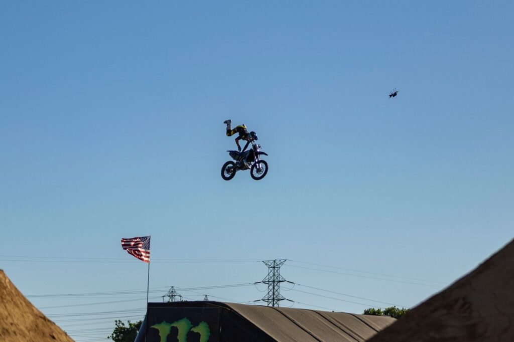 Motorcyclist performs an aerial stunt with a clear blue sky backdrop.